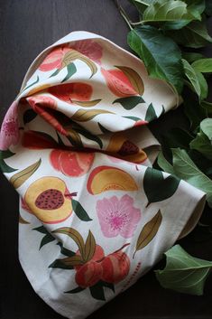 a close up of a cloth on a table with leaves and flowers in the background