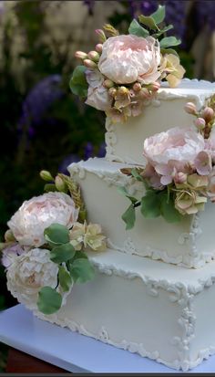 a three tiered white wedding cake with pink flowers on the top and green leaves