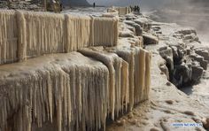 people standing on the edge of a cliff covered in ice