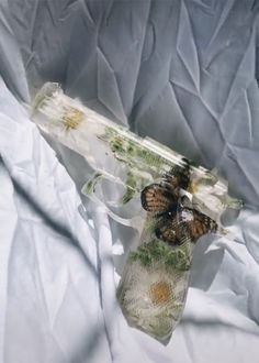 two butterflies sitting on top of a glass bottle with water in it's mouth