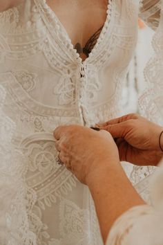 an older woman is helping another woman with her wedding dress