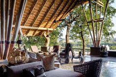 an outdoor living area with wicker furniture and large trees in the backgroud