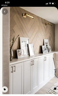 a room with white cabinets and pictures on the wall next to a rug in front of it