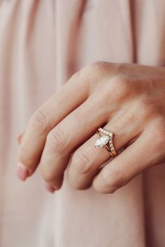 a woman's hand wearing a gold ring with a small white flower on it