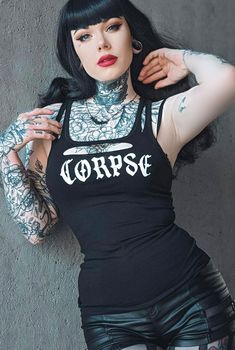 a woman with black hair and tattoos posing for the camera