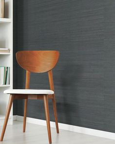 a wooden chair sitting in front of a book shelf next to a bookshelf