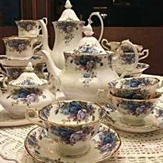 a table topped with lots of cups and saucers on top of a doily