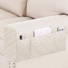 a white couch with an electronic device in the pocket