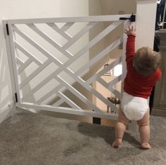 a toddler reaching up into a baby gate