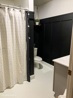 a bathroom with black and white shower curtain, toilet and sink in the corner area