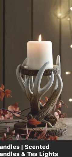 a candle that is sitting on top of a table with leaves and branches around it