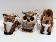 three small stuffed animals sitting next to each other on a white surface with wires in front of them