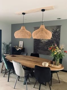 a dining room table with chairs and lights hanging from it's ceiling over it