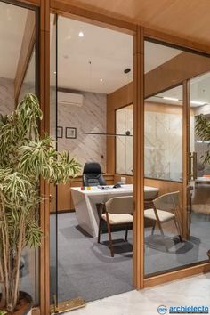 an office with glass walls and plants in the center, on top of a carpeted floor