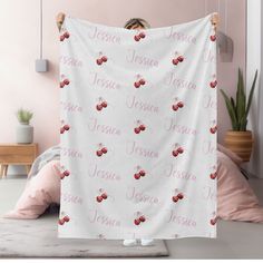 a woman is holding up a white blanket with cherries on it and the word jesus written in pink