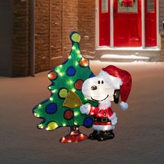 a snoopy christmas tree with lights on it and a person standing next to it