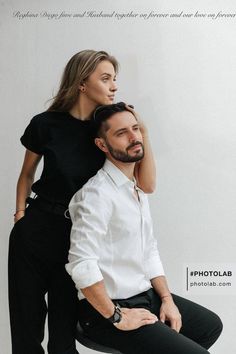 a man and woman sitting on top of each other in front of a white wall