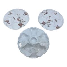 three plates with flowers on them sitting next to each other in front of a white background