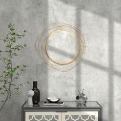 a white and black cabinet with a gold circle on the wall next to a potted plant