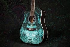 an acoustic guitar painted with blue and green swirls on a black wallpapered background