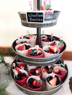 a three tiered tray filled with cupcakes covered in strawberries and berries