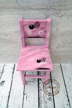 a pink wooden chair sitting on top of a white wood floor next to a wall