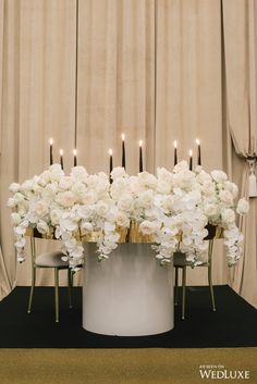 white flowers and candles are arranged on a table