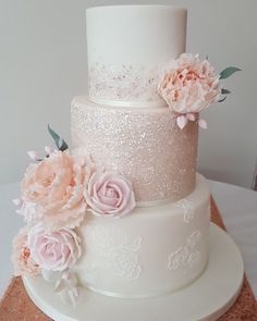 a three tiered wedding cake with pink flowers on the top and white frosting