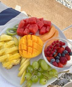 a white plate topped with fruit next to watermelon and grapes