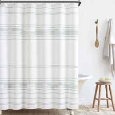 a white shower curtain in a bathroom next to a stool