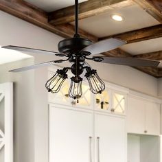 a ceiling fan in a kitchen with white cabinets and wood beams on the ceiling above it