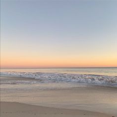 a person walking on the beach at sunset