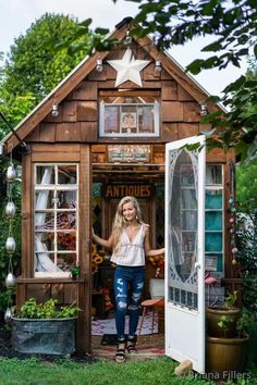 a woman standing in the doorway of a small wooden house