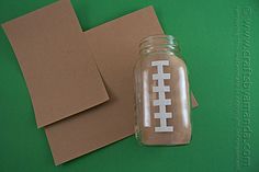 a mason jar with a football painted on it next to some cut out pieces of paper