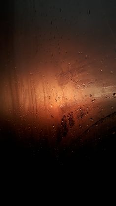 rain drops on the window of an airplane as it flies through the sky at sunset