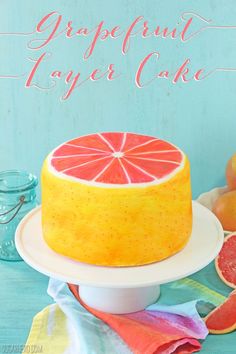 there is a cake that has grapefruit on the top and oranges in the background