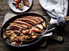 a pan filled with meat and vegetables on top of a wooden table