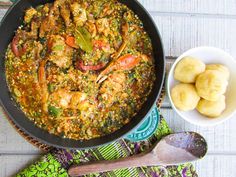 a pan filled with food sitting on top of a table next to a bowl of potatoes