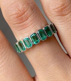 a woman's hand with an emerald ring on it