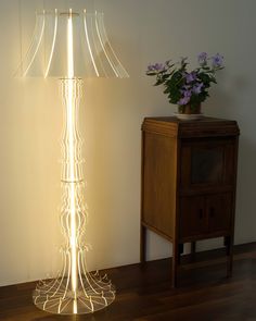 a lamp that is on top of a wooden table next to a vase with flowers