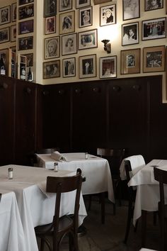 a dining room with white tablecloths and pictures on the wall