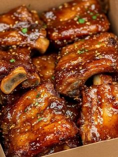 a box filled with chicken wings covered in sauce and seasoning sprinkled on top