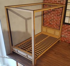 a wooden bed frame sitting on top of a hard wood floor next to a brick wall