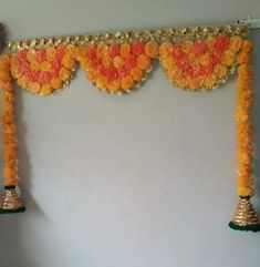 an arrangement of orange flowers and bells on the wall in front of a white wall