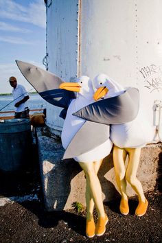 two plastic birds standing next to each other near a white building with graffiti on it