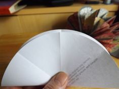 a person is holding an origami fan in their hand and the paper has been folded