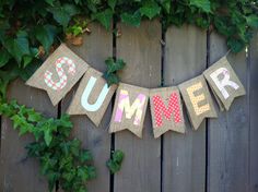 a banner that says summer hanging on a wooden fence with ivy growing around it and the word summer spelled out in large letters