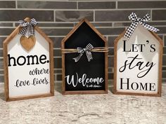 three small wooden houses are decorated with black and white signs that say, let's stay home