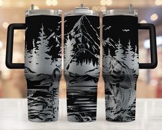 two black and white travel mugs sitting on top of a table next to each other