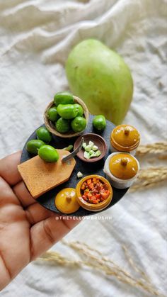 a hand holding a miniature plate with food on it and an apple in the background